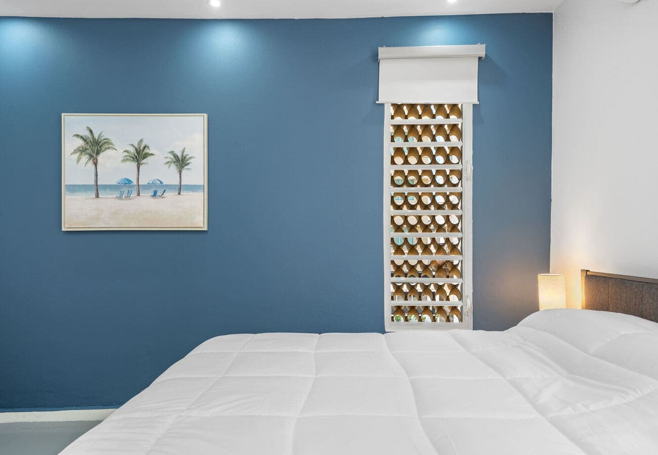 Queen bedroom with palm art & room-darkening shades