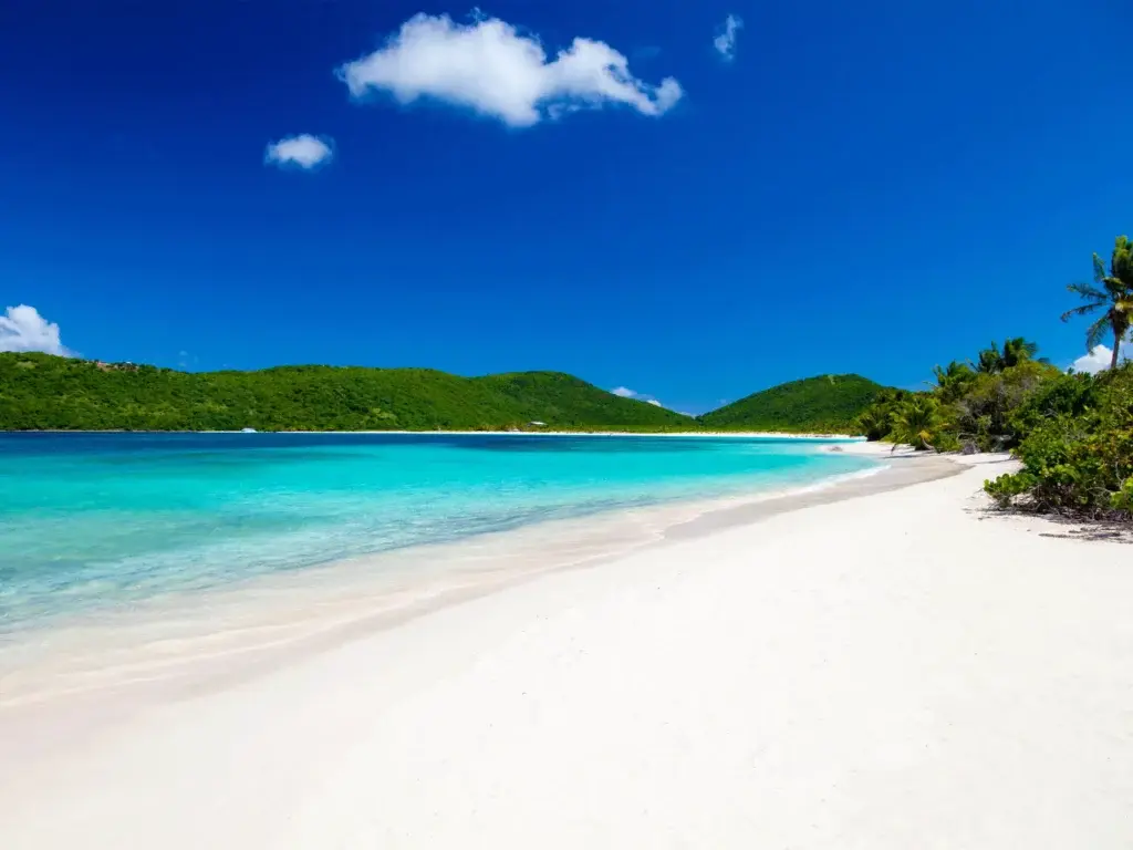 Una impresionante playa tropical con arena blanca, aguas turquesa y un cielo azul despejado.